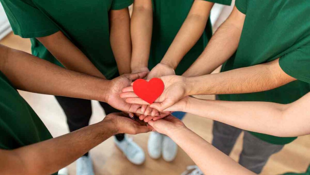 Volunteers holding a red heart together, symbolizing charitable giving for Bellevue small businesses donating goods vs cash.