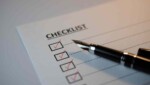 monthly bookkeeping checklist with red checkmarks and a pen on top of the paper.